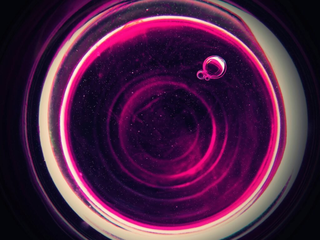 Vibrant abstract pink bubbles forming a circular pattern against a dark background, creating a cosmic feel.