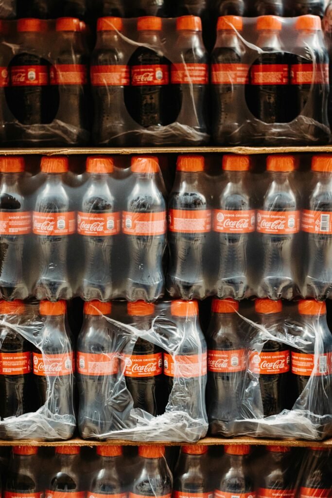Vertical shot of stacked Coca Cola bottles wrapped in plastic packaging.