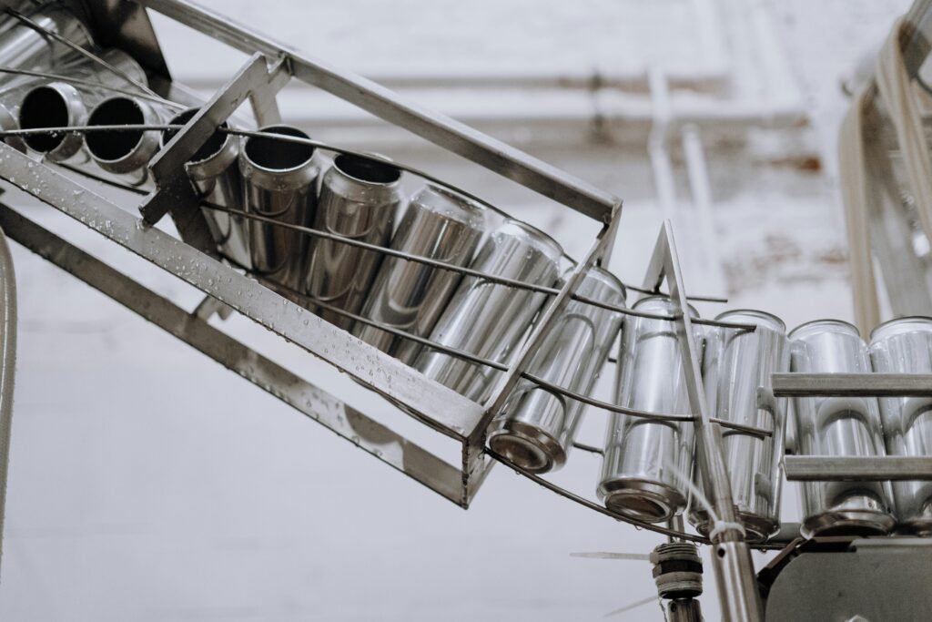 Conveyor belt with empty aluminum cans in a factory setting, showcasing production equipment.
