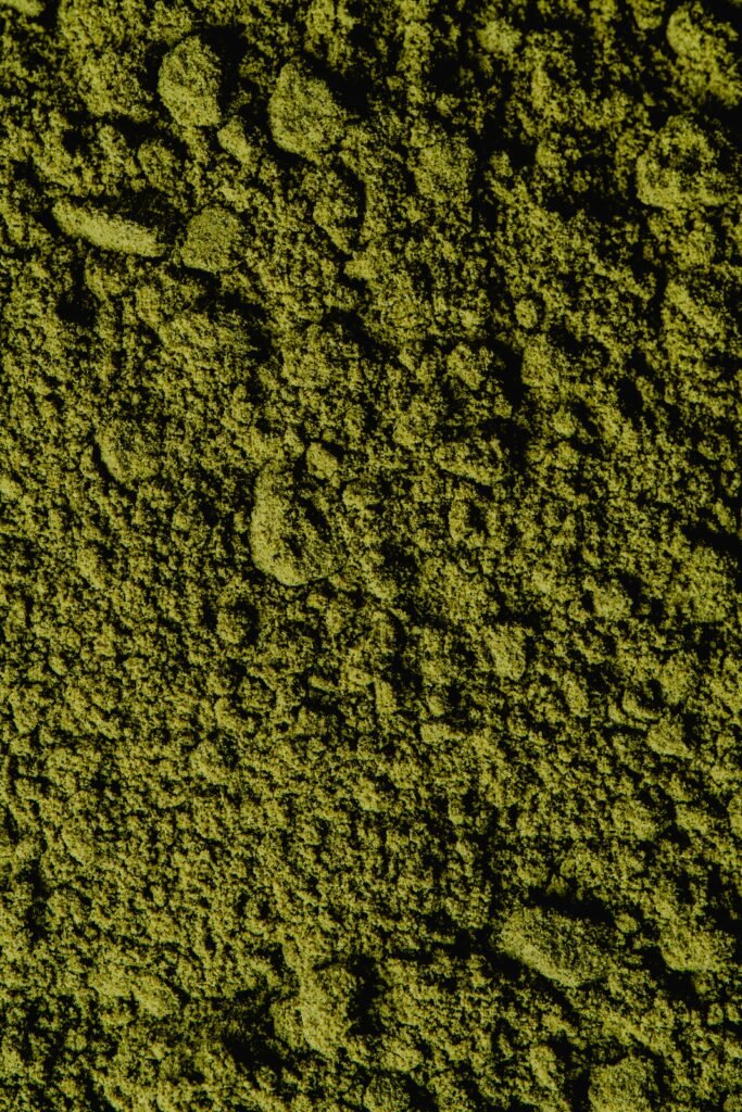 Closeup view of coarse green matcha powder texture, ideal for backgrounds and culinary themes.